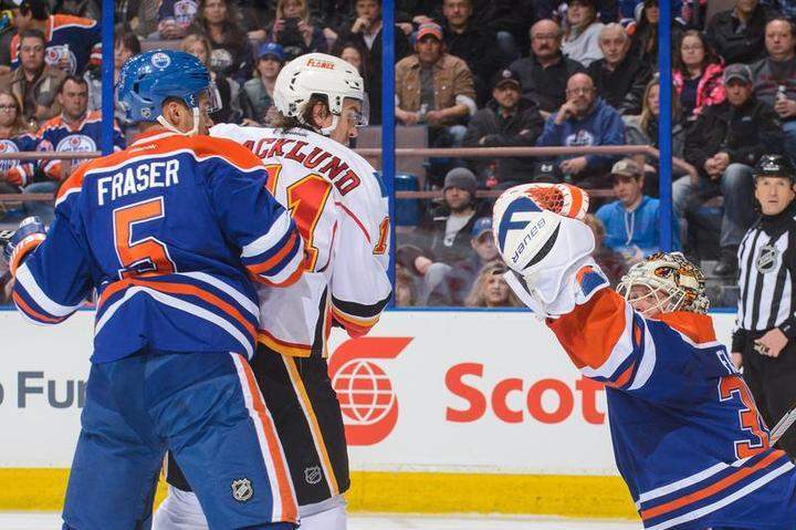 EDMONTON, AB - MARCH 22: Viktor Fasth #35 of the Edmonton Oilers makes a glove save in front of Mikael Backlund #11 of the Calgary Flames during an NHL game at Rexall Place on March 22, 2014 in Edmonton, Alberta, Canada.