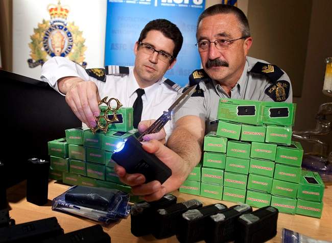 Calgary RCMP Sgt. Patrick Webb, right, and the Canadian Border Services Agency criminal investigation manager Richard Cuzzetto demonstrate a stun gun as they display a selection of recently seized stun guns, butterfly knives and brass knuckles at RCMP Southern Alberta District HQ in Calgary, Alta., Monday, May 9, 2011.The weapons were seized as part of a joint operation and as a result a Calgary man is facing numerous charges. THE CANADIAN PRESS/Jeff McIntosh.