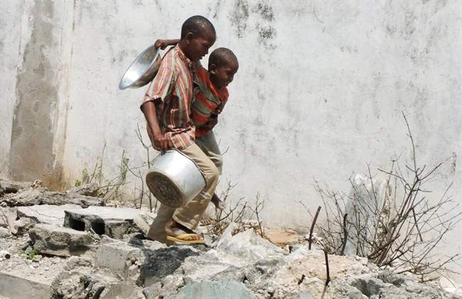 Two Somali children from southern Somalia, carrying a bowl and a pot, walk to a food distribution center in a camp for internally displaced people in Mogadishu, Somalia, Thursday, July 28 2011. Heavy fighting erupted Thursday in Somalia's capital as African Union peacekeepers launched an offensive aimed at protecting famine relief efforts from attacks by al-Qaida-linked militants, officials said. The al-Shabab militants already have killed men who tried to escape the famine with their families, saying it is better to starve than accept help from the West. The World Food Program says it cannot reach 2.2 million people in need of aid in the militant-controlled areas in southern Somalia because of insecurity. (AP Photo/Farah Abdi Warsameh).