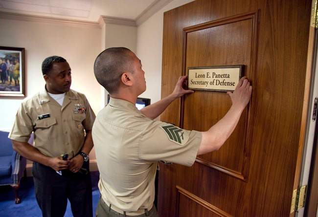 Marine Sgt. John Kang attaches the name plate of incoming Defense Secretary Leon Panetta to his office door at the Pentagon, Friday, July 1, 2011. (AP Photo/Evan Vucci).