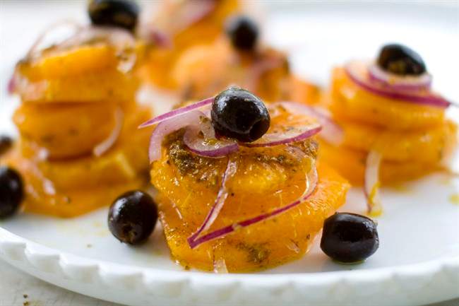 This photo shows an orange and red onion salad with warmed coriander oil.