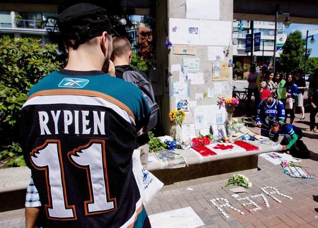 Tyler Stychyshyn wears a Manitoba Moose jersey as he pauses at a makeshift memorial for Rypien outside Rogers Arena in Vancouver, B.C., on August 17, 2011.