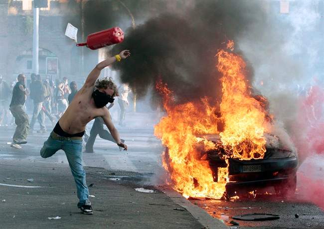 A protestor hurls a canister towards police next to a burning car during clashes in Rome, Saturday, Oct. 15, 2011. Protesters in Rome smashed shop windows and torched cars as violence broke out during a demonstration in the Italian capital, part of worldwide protests against corporate greed and austerity measures, entitled Occupy Wall Street. (AP Photo/Gregorio Borgia).