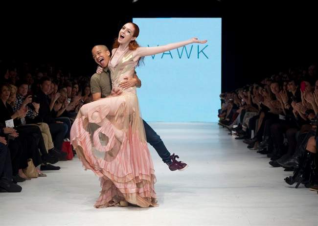 Designer Sunny Fong (left) catches a model as she stumbles on the runway at the end of the Vawk show on the runway at Toronto Fashion Week on Thursday October 20, 2011. THE CANADIAN PRESS/Chris Young.