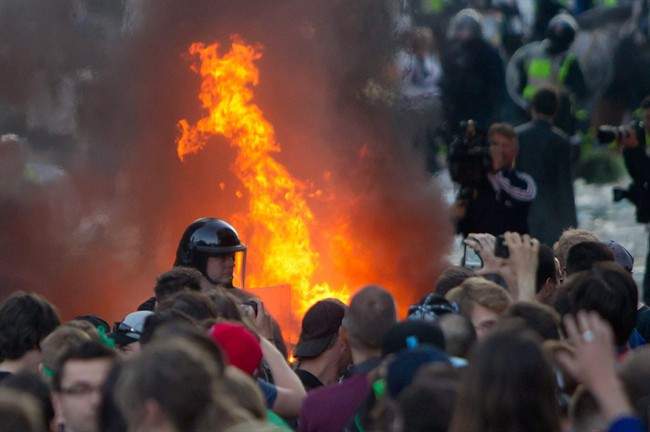 A car burns behind a police officer after a riot broke out after the Vancouver Canucks were defeated by the Boston Bruins in the NHL Stanley Cup Final in Vancouver, B.C., on Wednesday June 15, 2011. Vancouver police want the provincial government to change laws so officers have more power to search people for liquor in order to avoid violence like the Stanley Cup riot. THE CANADIAN PRESS/Darryl Dyck.