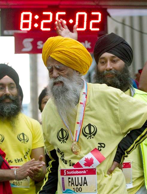 Fauja Singh, aged 100, grimaces and holds his back after crossing the line in the Toronto Waterfront Marathon in Toronto on Oct. 16, 2011. Singh died Monday at the age of 114.