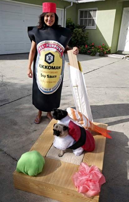 FILE- This file photo taken Oct. 4, 2009 shows Lisa Woodruff holding a pair of chop sticks alongside her 4-year-old pugs Mochi, foreground, and Olive dressed as sushi at their home in Huntington Beach, Calif. The pugs have been geisha girls, surfer girls and sushi over the years. (AP Photo/Richard Vogel, FILE).