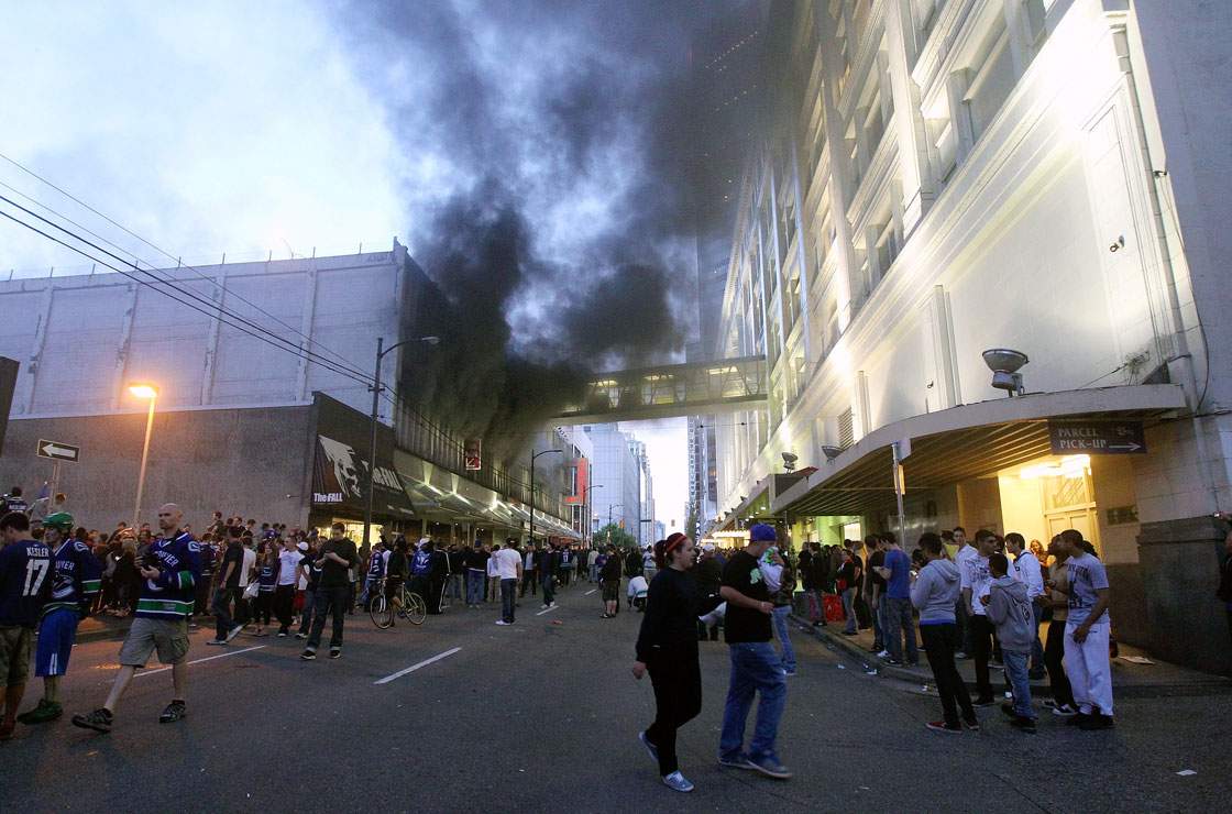 People walk in the street as smoke billows out of a building on June 15, 2011 in Vancouver, Canada. Vancouver broke out in riots after their hockey team the Vancouver Canucks lost in Game Seven of the Stanley Cup Finals.  