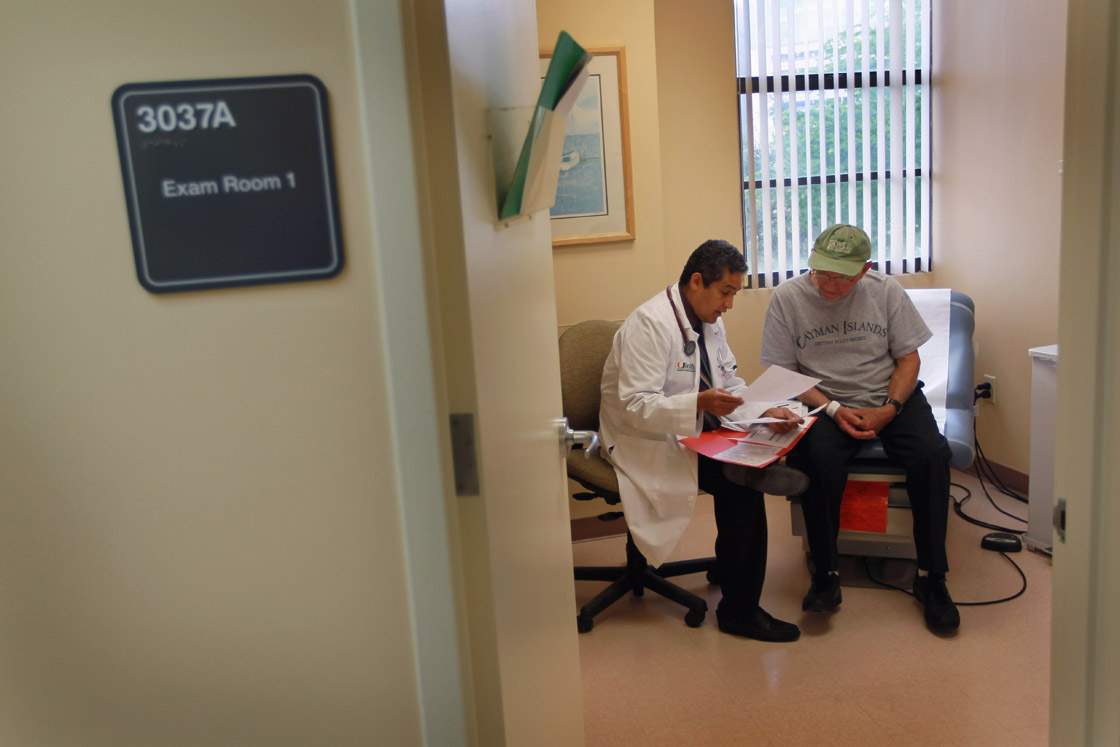 Dr. Olveen Carrasquillo (L), Chief of General Internal Medicine University of Miami, sits with Juan Gonzalez as he conducts a checkup on him.
