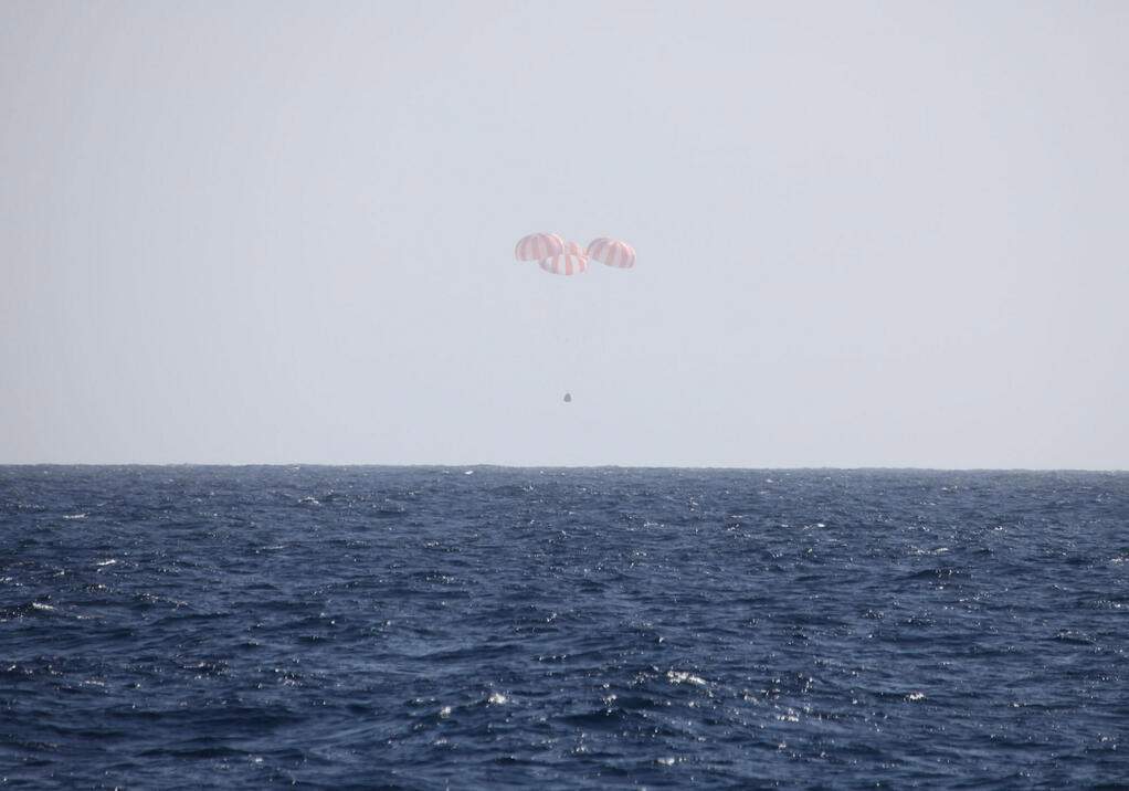 In this image provided by SpaceX, the Dragon capsule uses parachutes to descend to the Pacific Ocean off the coast of Mexico's Baja Peninsula after leaving the International Space Station. 