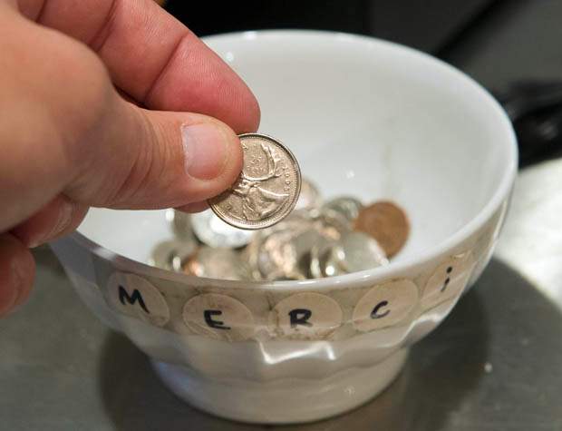 A customer drops a coin in a tip jar.