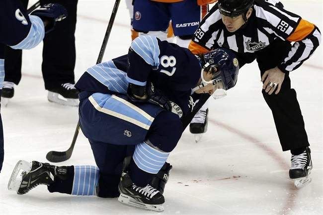 Pittsburgh Penguins center Sidney Crosby (87) is helped by referee Ian Walsh (29) after being hit in the face with a puck during the first period of an NHL hockey game against the New York Islanders in Pittsburgh, Saturday, March 30, 2013. 