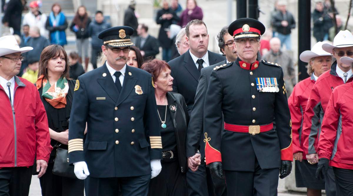 Widow Colleen Klein, centre, is escourted by dignitaries and White Hatters as she walks from city hall to the main public memorial service for former premier, and Calgary mayor, Ralph Klein in Calgary on Friday, April 5, 2013. THE CANADIAN PRESS/Larry MacDougal