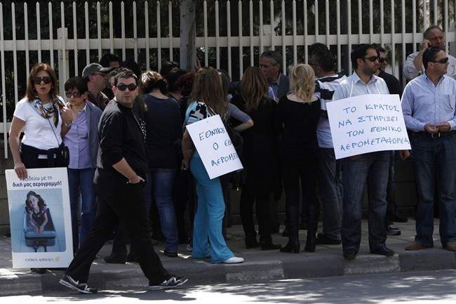 Employees of Cyprus Airways with banners, left, reading in Greek "travelling with my own airlines", right, "the state support the state-owned carrier" during a demonstration outside of the presidential palace in Nicosia, Cyprus, Wednesday, April 10, 2013.