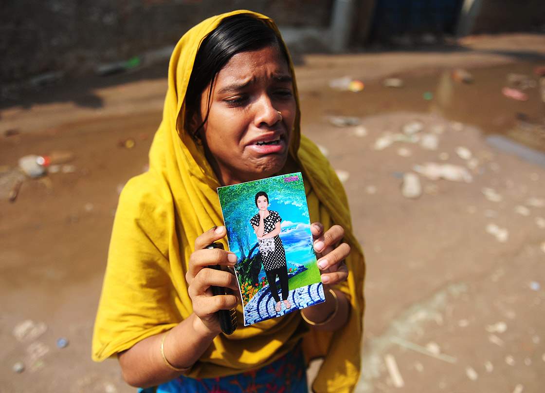 A Bangladeshi woman shows a portrait of her missing twin sister, believed trapped in the rubble.  (Getty Images)