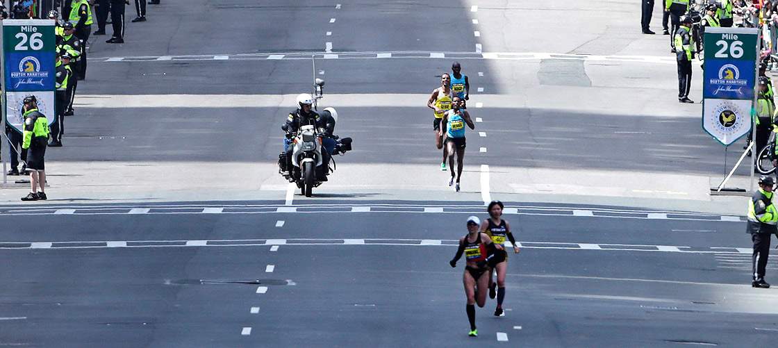 A motorcycle camera crew photographs the lead men’s finishers as they pass the 26th mile marker, which was dedicated to the victims of the Sandy Hook Elementary School shooting in Newtown, Conn., during the 2013 running of the Boston Marathon in Boston, Monday, April 15, 2013.