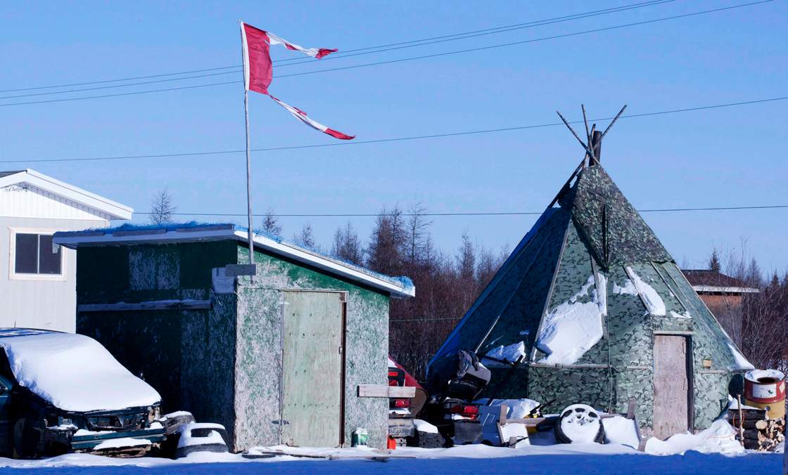 File photo - The remains of a Canadian flag can be seen flying over a building in Attawapiskat, Ont., on November 29, 2011. 