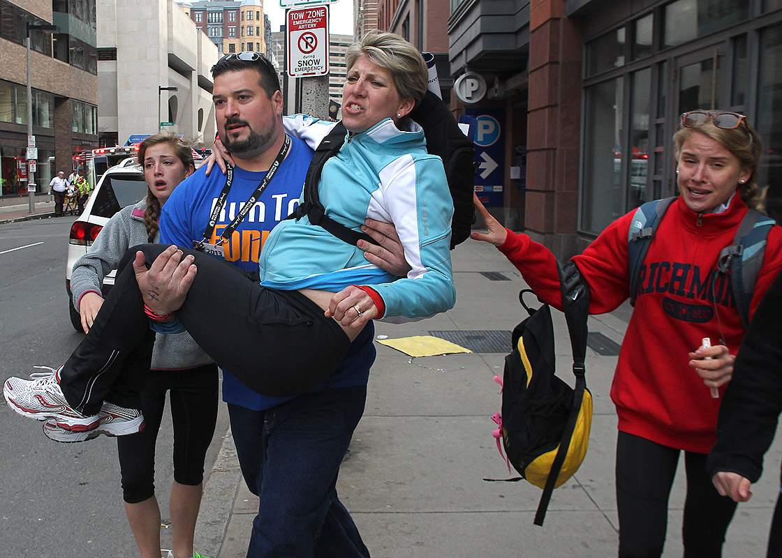 Former New England Patriots player Joe Andruzzi carries a woman from the scene on Exeter Street after two explosions went off on Boylston Street near the finish line of the 117th Boston Marathon on April 15, 2013.