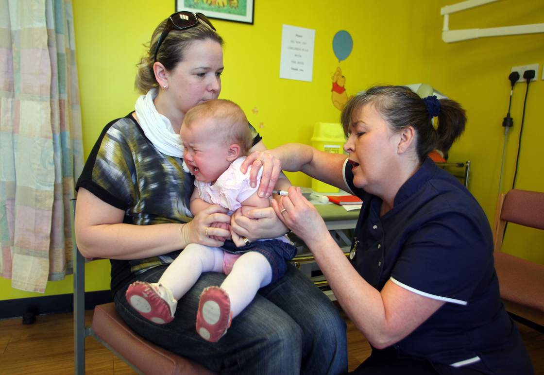 14-month-old Amelia Down sits on the lap of her mother Helen (L) as she receives the combined Measles Mumps and Rubella (MMR) vaccination at on April 20, 2013. 