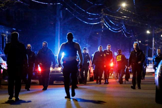 Police officers walk near a crime scene Friday, April 19, 2013, in Watertown, Mass. A tense night of police activity that left a university officer dead on campus just days after the Boston Marathon bombings and amid a hunt for two suspects caused officers to converge on a neighborhood outside Boston, where residents heard gunfire and explosions.