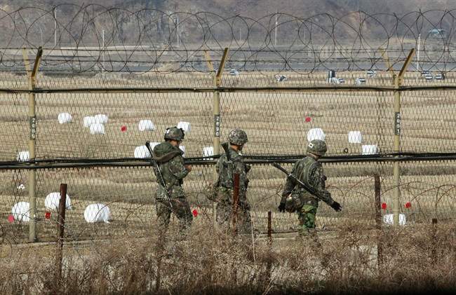 South Korean army soldiers patrol along a barbed-wire fence near the border village of Panmunjom in Paju, South Korea, Monday, April 8, 2013.