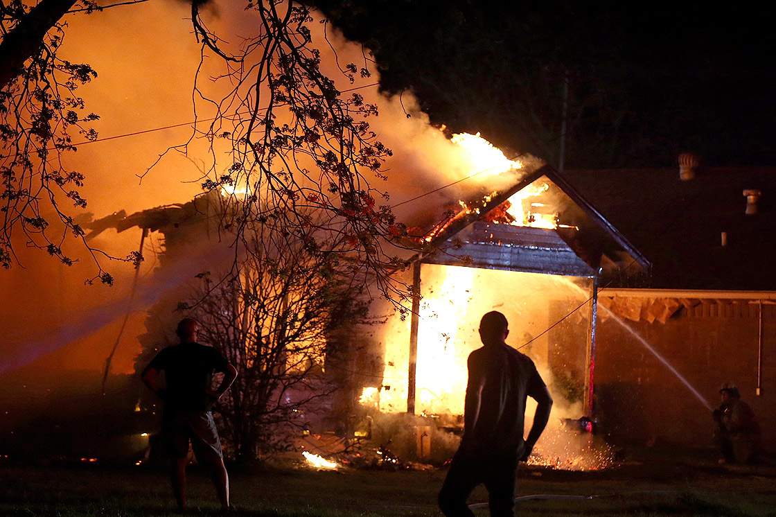 A person looks on as emergency workers fight a house fire after a near by fertilizer plant exploded Wednesday, April 17, 2013, in West, Texas.