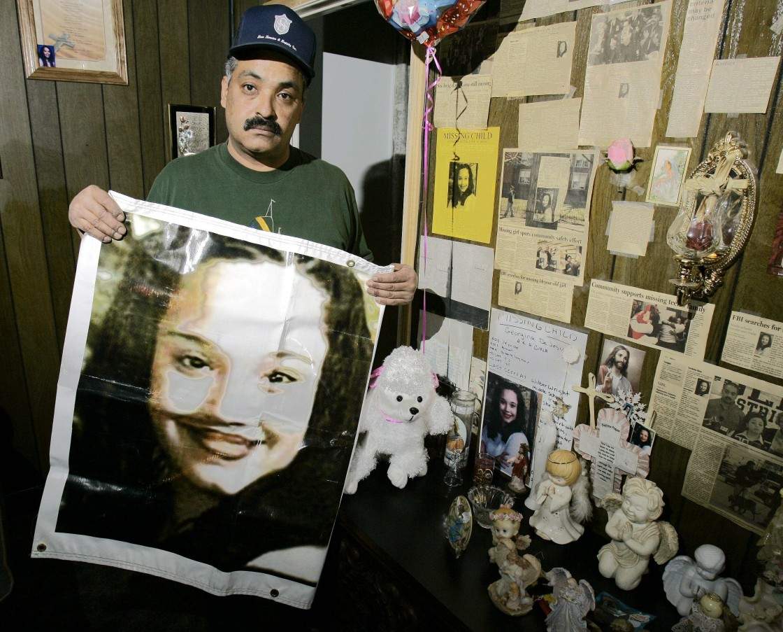 In this Friday, March 3, 2004 file photos shows Felix DeJesus, holding a banner showing his daughter’s photograph, standing by a memorial in his living room in Cleveland. Cleveland police say two women who went missing as teenagers about a decade ago have been found alive in a residential area about two miles south of downtown. Cheering crowds gathered Monday night on the street near the home where police say Amanda Berry, Gina DeJesus and a third woman were found earlier in the day. The identity of the third woman hasn’t been confirmed.