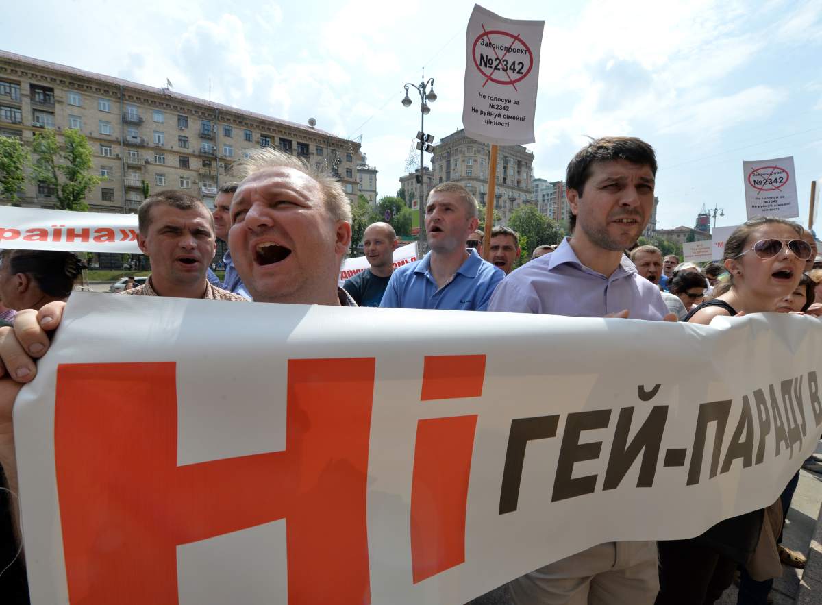 People shout slogans as they hold placards and a banner reading "No gay parade!" during an anti-gay rally in the center of Ukrainian capital of Kiev on May 14, 2013.  