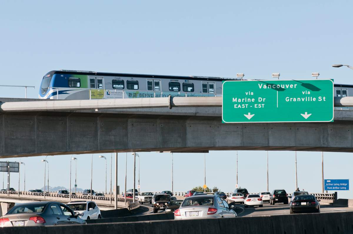 A Canada Line public transit SkyTrain passes over cars on the Arthur Laing Bridge on its way to Vancouver International Airport. 
