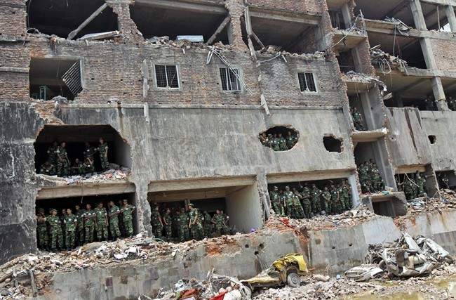 Bangladesh army soldiers stand at the wreckage of a Bangladeshi garment factory building to offer prayers for the souls of the 1,127 people who died in the structure’s collapse last month, in Savar, Bangladesh, Tuesday, May 14, 2013. 