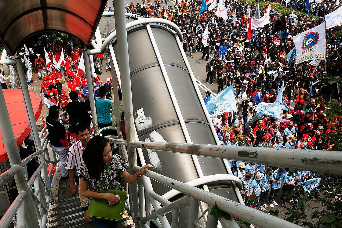 Office workers climb an overpass to cross Jakarta’s main thoroughfare as May Day demonstrators march to the Presidential Palace during a demonstartion on May 1, 2013 in Jakarta, Indonesia. Tens of thousands of workers and labour activists marched through Jakarta’s central business district, demanding the implementation of higher minimum wages and better working conditions. Getty Images