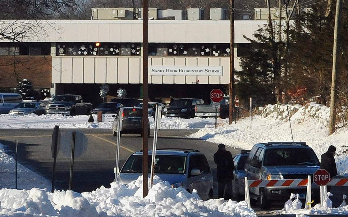 FILE - In this Jan. 3, 2013 file photo, police block the road at the entrance to the new Sandy Hook Elementary School on the first day of classes in Monroe, Conn.