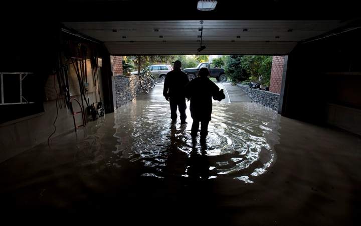 A couple is silhouetted as they walk out of their flooded garage near the Elbow River in Calgary, Ab. Saturday, June 22, 2013. 
