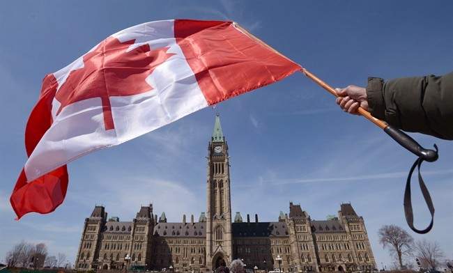 A Canadian flag attached to a ski pole is waved on Parliament Hill in Ottawa on Monday, April 15, 2013.