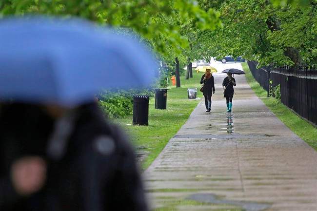 FILE - Pedestrians shield themselves from the rain in downtown Halifax, N.S. on Saturday, June 8, 2013.