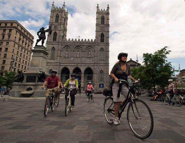 Chantal Doiron, right, leads a bike tour past Notre Dame Basilica Friday, May 17, 2013 in Montreal. 