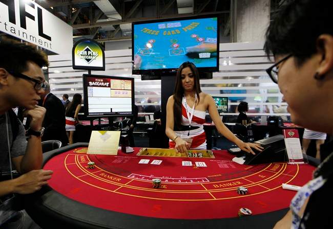 In this file photo taken on Thursday, May 23, 2013, an attendant demonstrates the game of baccarat on a baccarat gaming table during the Global Gaming Expo Asia in Macau.