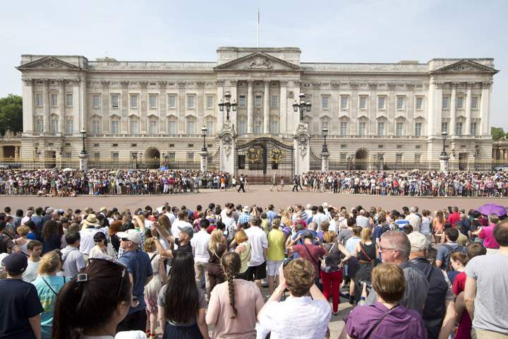 Crowds of tourists gather on the steps of the Queen Victoria Memorial Statue outside Buckingham Palace in central London on July 22, 2013.