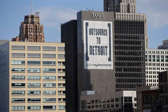 In this July 12, 2013, photo an Outsource to Detroit banner from GalaxE.Solutions is seen on a Detroit building.