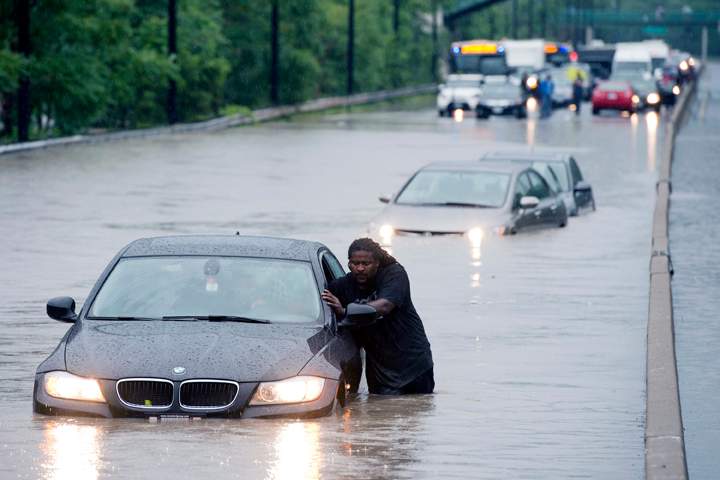A tow truck driver floats a car out of the Don Valley Parkway in Toronto on Monday, July 8 2013. (THE CANADIAN PRESS).