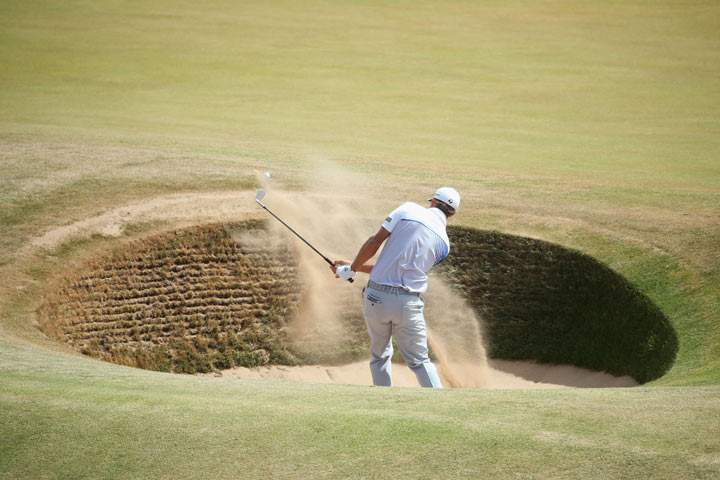 Dustin Johnson of the United States hits out of the bunker on the 4th hole during the final round of the 142nd Open Championship at Muirfield on July 21, 2013 in Gullane, Scotland. (Photo credit: Andrew Redington/Getty Images)