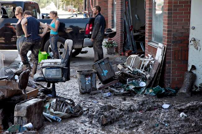 Mud and building contents litter the sidewalk as clean up work commences on downtown places of business in High River.