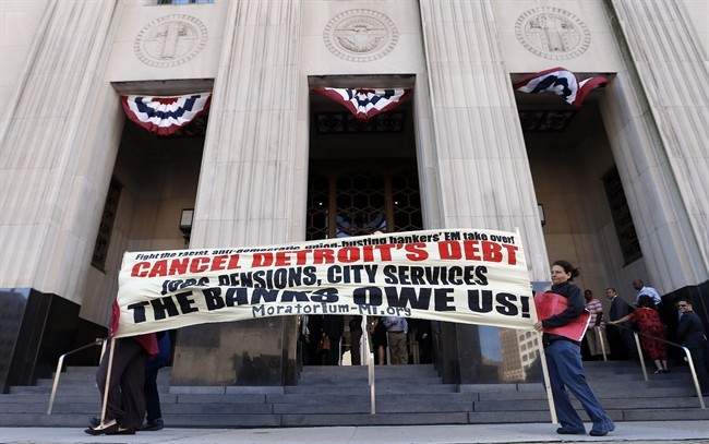 Protesters carry a sign outside the Levin Federal Courthouse in Detroit, Wednesday, July 24, 2013. 