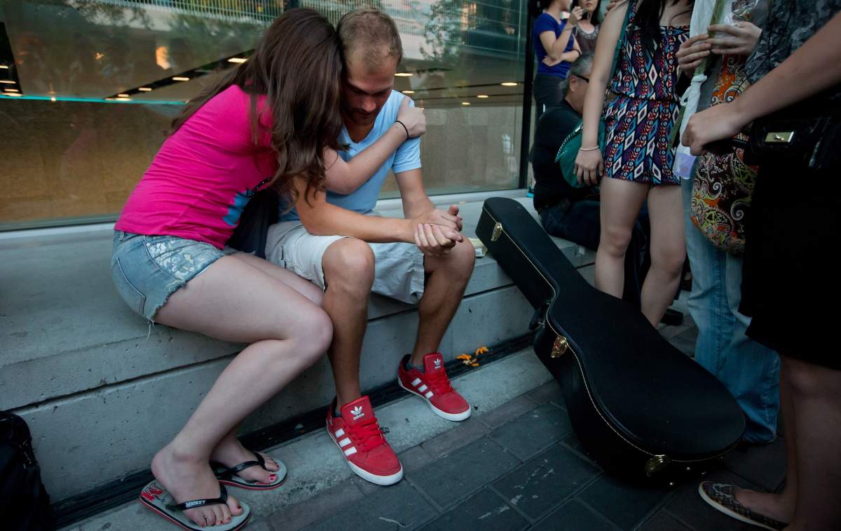 Richard Monteith, second left, cousin of late Canadian actor Cory Monteith, is comforted by a woman during a candlelight vigil outside the Fairmont Pacific Rim Hotel in Vancouver, B.C., on Friday July 19, 2013. Monteith's body was found in a room at the hotel July 13. 