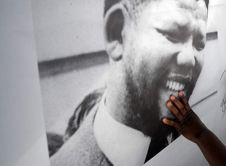 A man touches a Nelson Mandela portrait outside the Medi Clinic Heart hospital where former South African president Nelson Mandela lays in critical condition in Pretoria on July 6, 2013. Emotional crowds gathered outside the hospital, as relatives and clan elders made preparations for the revered former South African leader's final journey. Singing supporters amassed outside the Pretoria hospital where the 94-year-old anti-apartheid hero was fighting for his life.