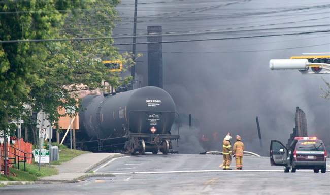 Smoke rises from railway cars that were carrying crude oil after derailing in downtown Lac Megantic, Que, Saturday, July 6, 2013. THE CANADIAN PRESS/Paul Chiasson