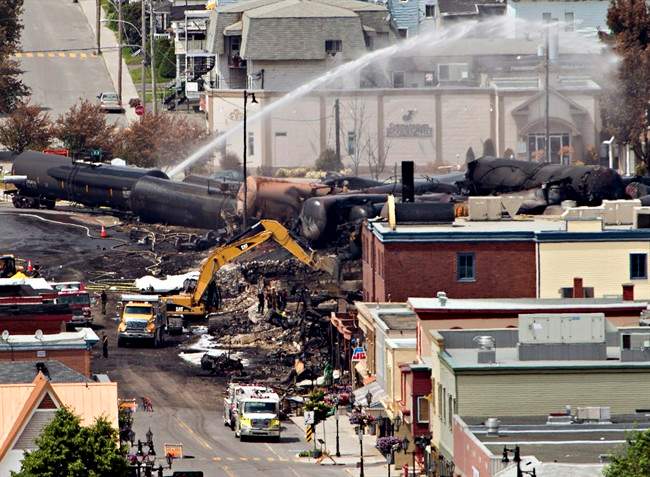 Searchers dig through the rubble for victims of the inferno in Lac-Megantic, Quebec, Monday, July 8, 2013, as firefighter continue to hose down tanker cars to prevent explosions. A runaway train derailed igniting tanker cars carrying crude oil early Saturday. 