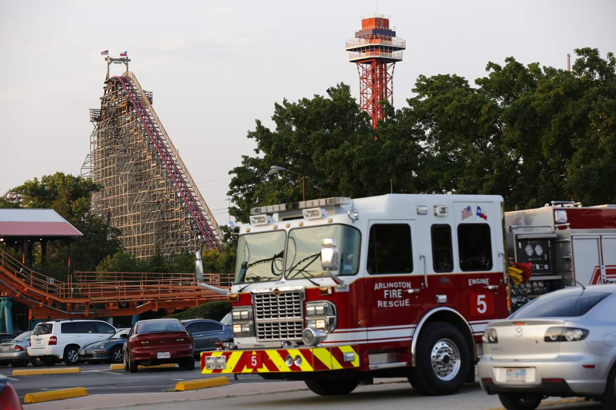 Emergency personnel are on the scene at Six Flags Over Texas in Arlington, Texas, after a woman died on the Texas Giant roller coaster, background left, on Friday, July 19, 2013.