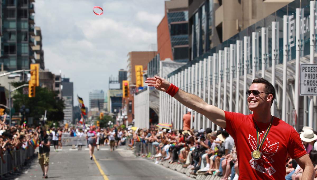 Olympic Gold Medalist in Barcelona, Mark Tewksbury tosses Olympic Team wristbands into the crowd in the Toronto Gay Pride Parade which attracts a million people who line the route in Toronto, June 30, 2013. Steve Russell/Toronto Star via Getty Images