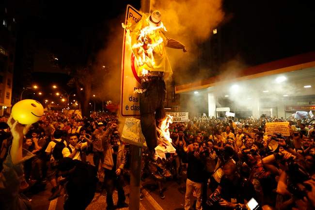 Protesters burn a puppet that symbolizes Rio de Janeiro State Governor Sergio Cabral during a demonstration near Guanabara Palace in Rio de Janeiro, Brazil, Monday, July 22, 2013. Police and anti-government protesters clashed outside the palace hosting Pope Francis welcoming ceremony. About an hour after the pope concluded his short speech, police began cracking down on the protests, firing rubber bullets in an effort to disperse the crowd. (AP Photo/Victor R. Caivano)